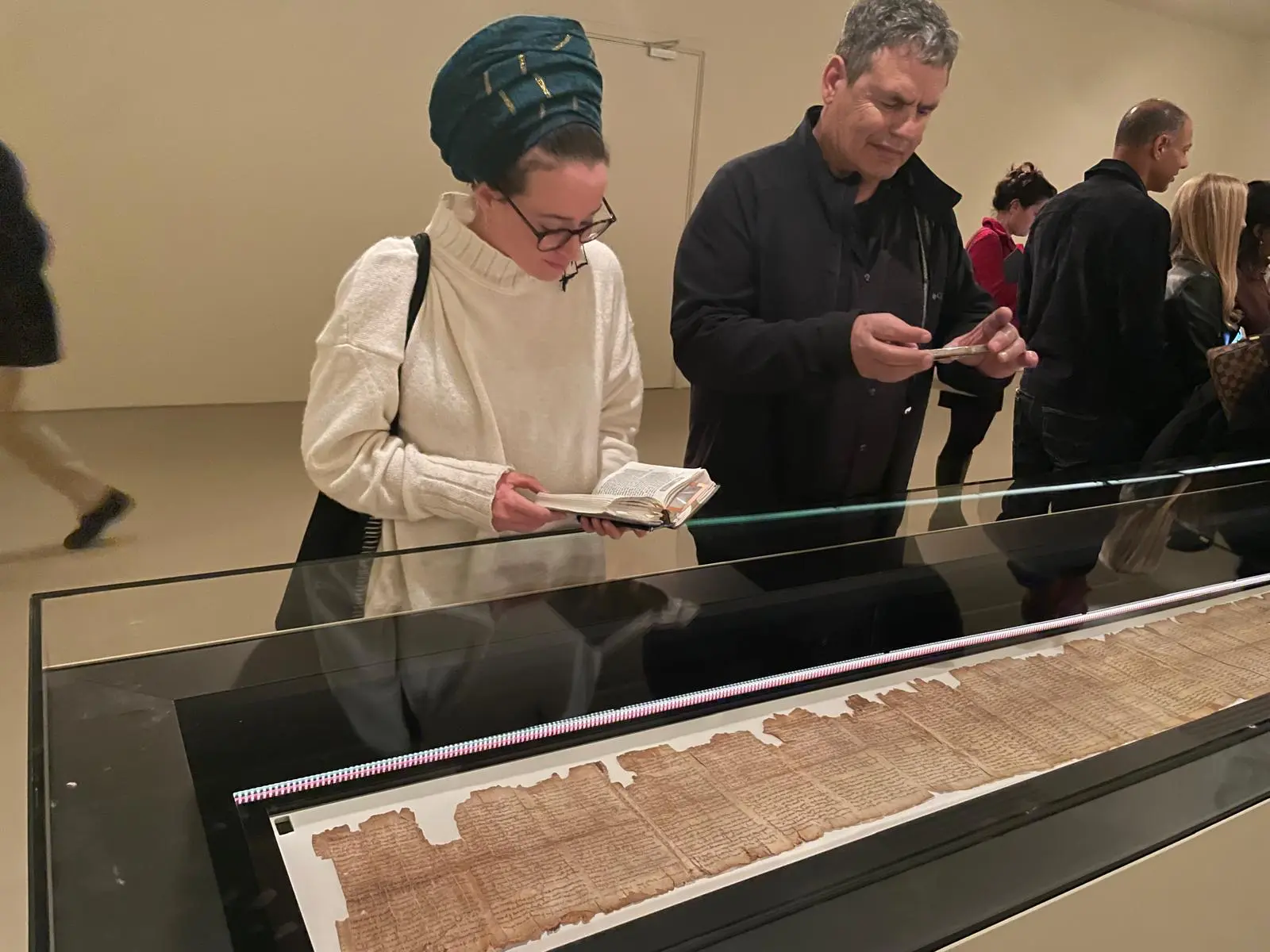 Посетители рассматривают семиметровый Великий свиток Исаии в специальном зале с контролируемым климатом. (Rossella Tercatin / Times of Israel)